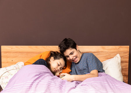 Couple in bed watching a movie or news together on a phone.