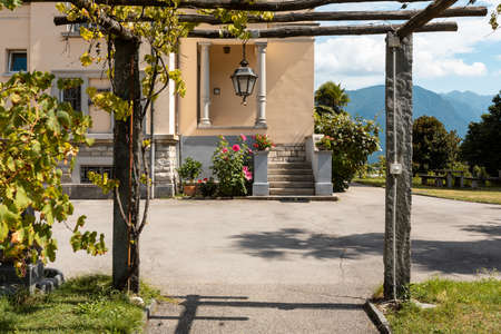 Ancient villa entrance with stone porch and wooden logs. Nobody inside. Sunny summer dayの写真素材