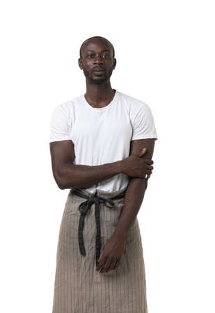 African boy with apron poses frontal on white background in photo studio. Half-length portrait. Copy-spaceの写真素材