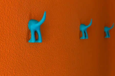 Detail of a coat hanger in the shape of a dog's seat with the tail raised. Orange wall. Nobody insideの写真素材