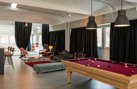 Detail of the room with a pool table, a sitting area with armchairs and sofas and a bar corner....