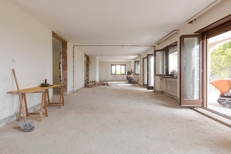 Large bright room with many windows of an old villa undergoing demolition and renovation. The walls...