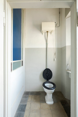 Front view of the toilet room with blue toilet board. On the left is a blue window. Interior of an abandoned villa to be restored.の写真素材