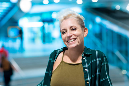 Portrait of a woman with short blond hair. She is wearing an open checkered shirt and a green shirt underneath. Urban scene.の写真素材