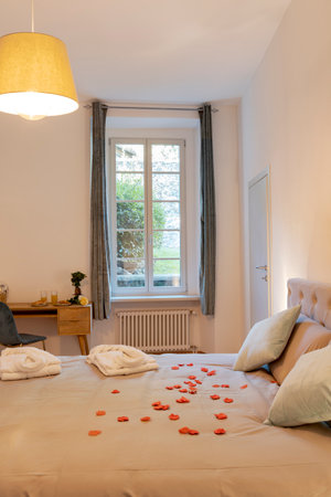 Intimate and romantic bedroom with large bed, paquet floor. Above the bed are large pillows and rose petals. Nobody insideの写真素材