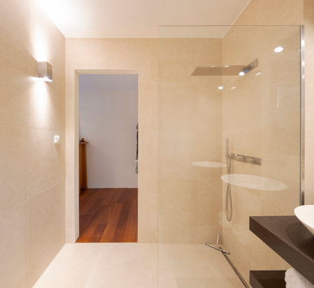 Modern bathroom front view with large light marble slabs. Front view of large shower with a glass pane as a partition. Nobody inside.の写真素材