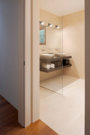 Modern bathroom with large light marble slabs. There are two sinks with a large mirror illuminated by spotlights. Nobody insideの写真素材