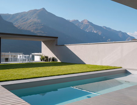 Swimming pool with a view of the Swiss Alps. There is a garden and a patio. Nobody insideの写真素材