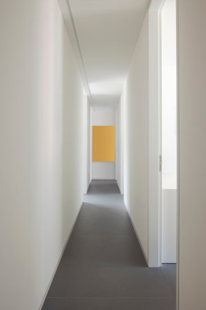 Front view of a hallway with white walls, open doors on the sides from which sunlight enters. Nobody insideの写真素材