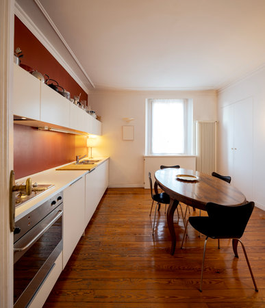 Elegant kitchen with red backsplash and white walls. Antique apartment interior with modern furniture. Nobody insideの写真素材
