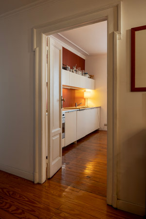 Detail of a modern kitchen can be seen from the open door in the hallway. Vintage apartment interior with modern furniture. Nobody insideの写真素材