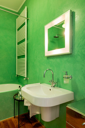 Bathroom with parquet floors and green walls, bathtub with shower and white curtain. Interior vintage apartment with modern furniture. Nobody insideの写真素材