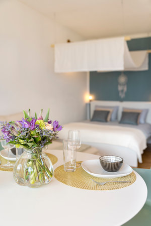 Detail of a place set for lunch, with a plate, cutlery and a glass. There is a bouquet of fresh flowers. Copy spaceの写真素材