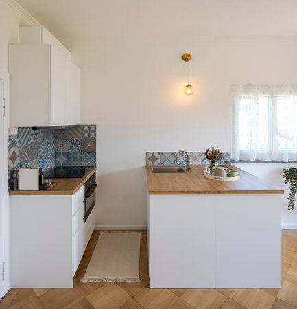 Front view of a small artistic kitchen with a wooden countertop and a small bright window. No one insideの写真素材