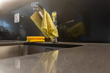 Detail of a steel sink with a rag and a yellow sponge near it. Kitchen