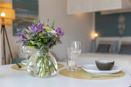 Detail of a place set for lunch, with a plate, cutlery and a glass. There is a bouquet of fresh flowers. Copy spaceの写真素材