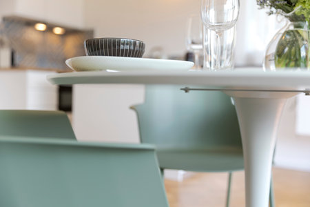 Detail of turquoise chair and white table with dishes on it. The kitchen is in the background. Nobody insideの写真素材