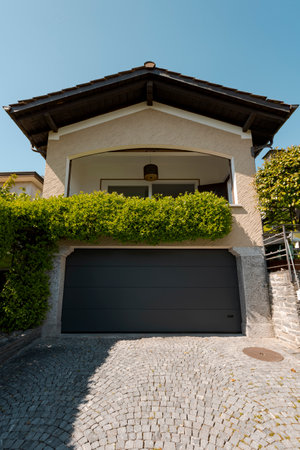 Exterior view of a villa with parking and balcony. A beautiful green plant climbs up the facade. Clear blue skyの写真素材