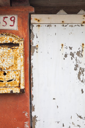 Detail of a mailbox on an orange wall with the number 59. It's all run downの写真素材