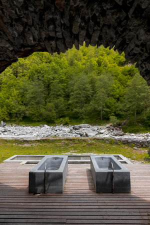 Thermal bath tubs with a view of the river and Swiss nature. View from inside a cave. Nobody inside, front view,の写真素材