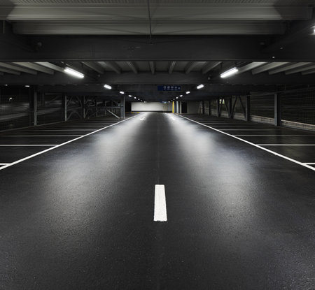 Modern underground garage with lamps illuminating the scene. Parking lines are drawn on the floor. No one insideの写真素材