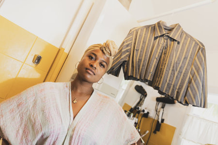 Portrait of young girl in her bathroom with a badly cut shirt hanging behind.の写真素材