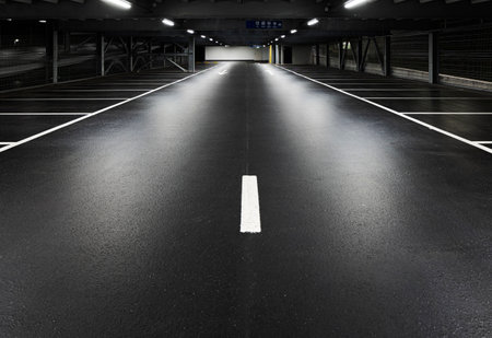 Modern underground garage with lamps illuminating the scene. Parking lines are drawn on the floor. No one insideの写真素材