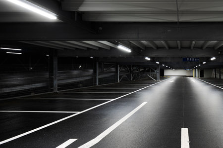 Modern underground garage with lamps illuminating the scene. Parking lines are drawn on the floor. No one insideの写真素材