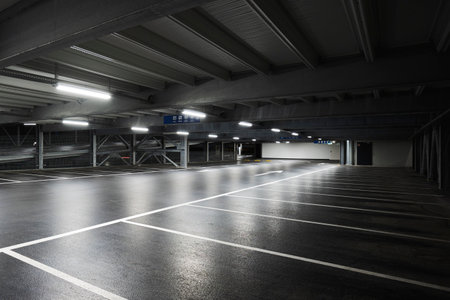 Modern underground garage with lamps illuminating the scene. Parking lines are drawn on the floor. No one insideの写真素材