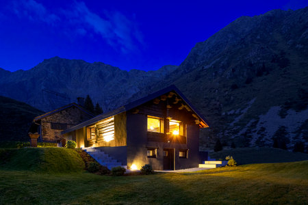 Modern mountain chalet in the middle of the evening as the sun sets and the night rises. Beautiful and evocative colours. Romance guaranteed. The place is the south of Switzerlandの写真素材
