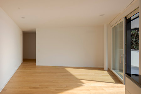 Empty room shot frontally with a white wall in front and a door on the left and a window on the right.の写真素材