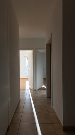 Hallway with white walls and tiles. There are open doors showing the rooms. Nobody insideの写真素材