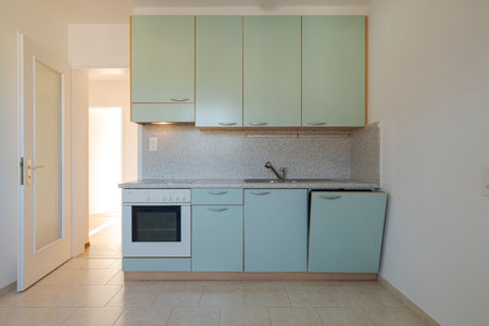 Front view of an old ugly teal kitchen with a white old oven. Nobody insideの写真素材