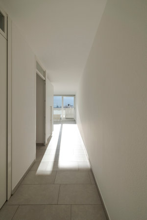 Front view of a corridor with the door open and the sun coming in and creating a very long shadow on the floor. Nobody insideの写真素材