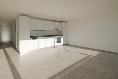 Renovated house interior with a white kitchen lit by the sun. White walls, no one insideの写真素材