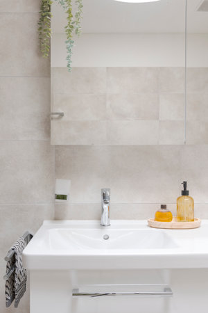 Interior of a modern bathroom. Front view of the sinks with a mirror and liquid soaps in front. Everything is new, clean and very bright. There is even a towel on the sideの写真素材