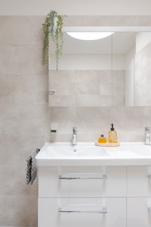 Interior of a modern bathroom. Front view of the sinks with a mirror and liquid soaps in front. Everything is new, clean and very bright. There is even a towel on the sideの写真素材