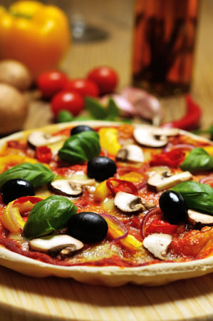  pizza on wooden board and some ingredients in the backgroundの写真素材