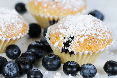 three soft blueberry muffins with powdered sugar on dark slateの写真素材