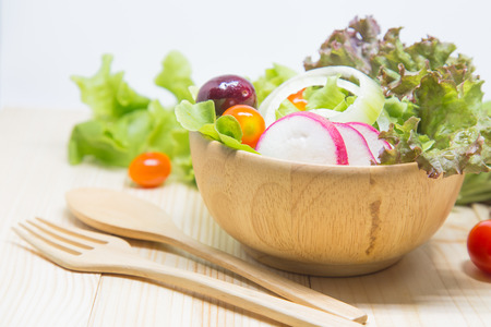 Salad in a wooden bowl on a wooden table, lettuce, tomatoes, cherries.の写真素材