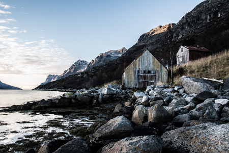old wooden cabins near the water with mountains behindの写真素材