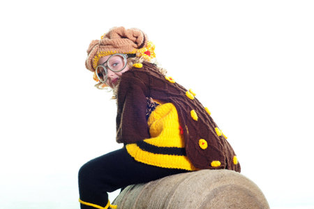 The girl in a knitted suit sits on the big ball of threads