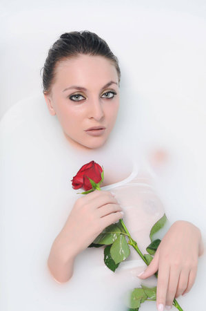 The beautiful woman in a bathroom with flowersの写真素材