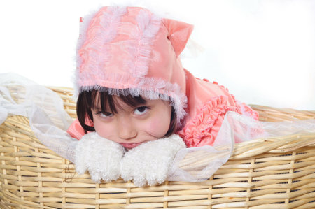 A beautiful girl with cute facial expression lying in a basketの写真素材