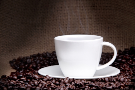 Cup of coffee with coffee beans on a beautiful brown background の写真素材