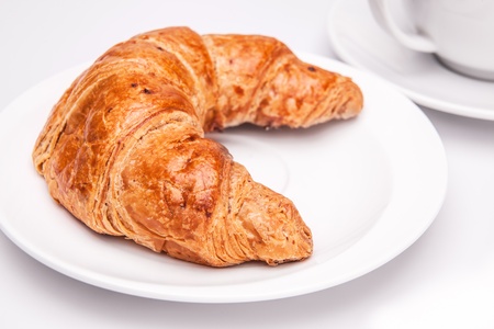 Delicious croissant and a cup of coffee on white backgroundの写真素材