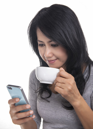 Beautiful woman texting on her mobile phone and drinking a coffee  の写真素材