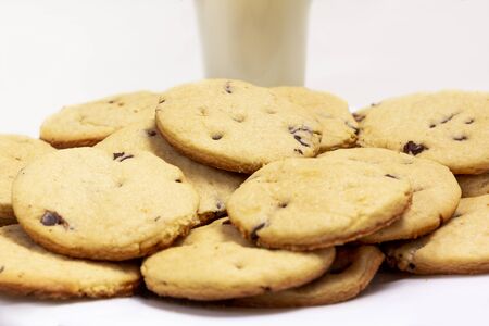 Delicious chocolate chip cookies plate with a glass of milk on the background. on a white Isolated backgroundの写真素材