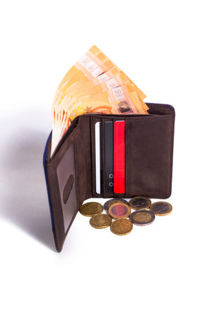 A Standing leather wallet with money and some coins coming out of it on a white background