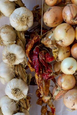 A close grouping of strings of garlic onions and chillies, principle ingredients in mediterranean cooking.の写真素材